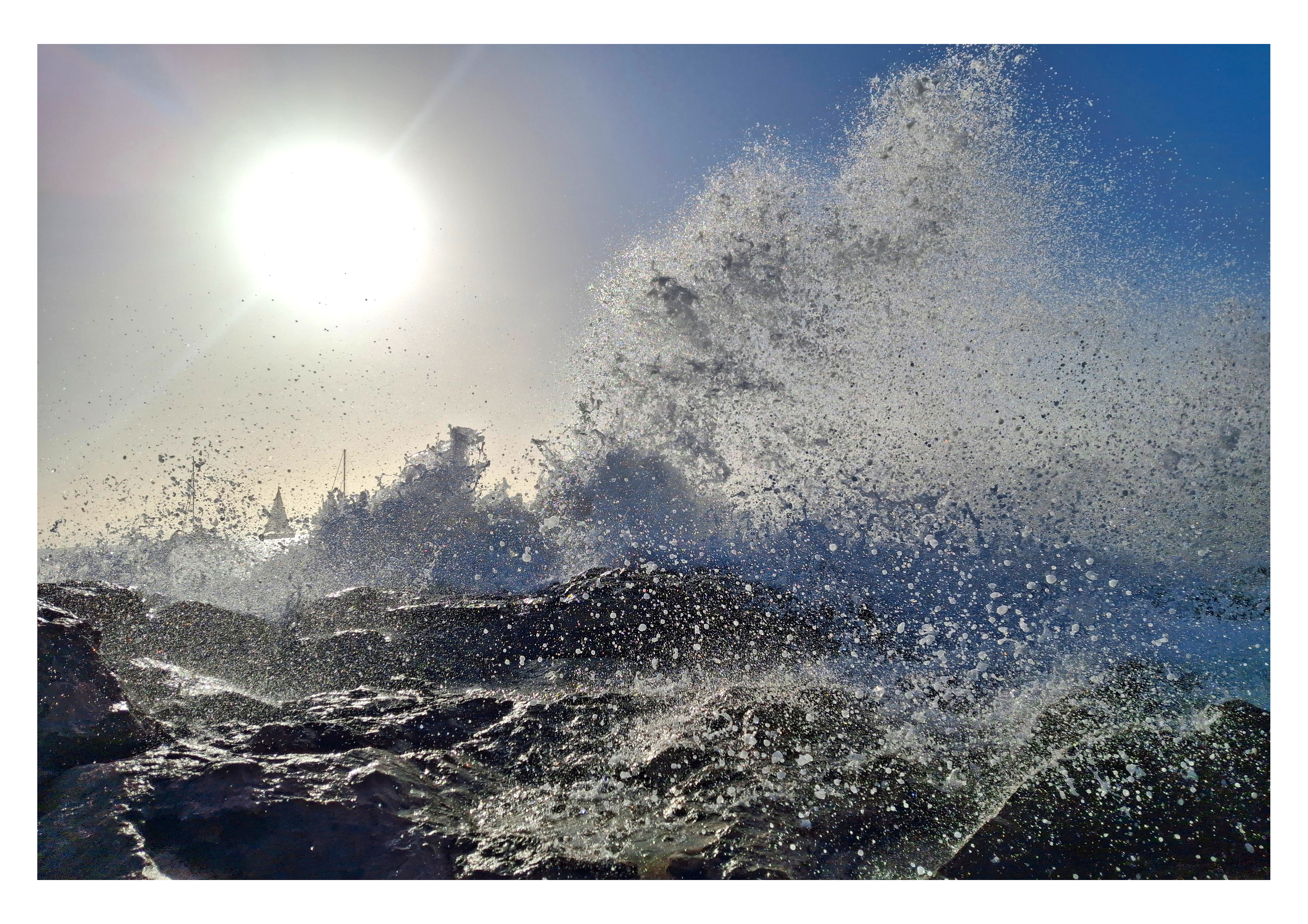 Photo validée pour la plaque aluminium : une vague éclate sur les rochers au soleil, en format horizontal